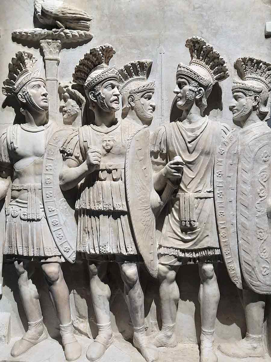 Ancient wall carvings depicting Praetorian Guard soldiers serving Roman emperors in ceremonial formation